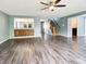 Spacious living room with modern flooring, a built-in bar, and an open staircase at 625 Streamside Dr, Greenfield, IN 46140