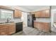 The kitchen has wood cabinets, a black dishwasher and refrigerator, and luxury vinyl plank flooring at 645 W Stop 11 Rd, Indianapolis, IN 46217