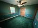 Bedroom featuring a ceiling fan, classic wood trim, green carpet, and closet doors at 7140 N Michigan Rd, Fairland, IN 46126