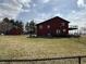 View of two-story home with red siding, black chain link fence, deck, and a grass lawn at 7140 N Michigan Rd, Fairland, IN 46126