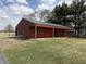 Red, one-story home with green trim and roof, and a covered porch, surrounded by a brick-lined walkway and green lawn at 7140 N Michigan Rd, Fairland, IN 46126
