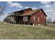 Two-story red home with wraparound deck on a sunny day at 7140 N Michigan Rd, Fairland, IN 46126