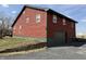View of two-story home with red wood siding, garage, garden bed, and black asphalt driveway at 7140 N Michigan Rd, Fairland, IN 46126