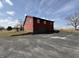 View of two-story home with red wood siding, garage, paved driveway, and black chain link fence at 7140 N Michigan Rd, Fairland, IN 46126