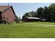 Charming exterior view of the home featuring a lush green lawn, red siding, and a separate garage at 7140 N Michigan Rd, Fairland, IN 46126