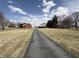 Long driveway leading to the red house and outbuildings set against a partly cloudy sky at 7140 N Michigan Rd, Fairland, IN 46126