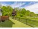 Artificial grass backyard featuring a dark tree inside an iron fence with mature trees in the background at 7218 Antiquity Dr, Carmel, IN 46033