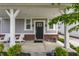 Covered front porch with white seating, brick accents, modern black door and fresh landscaping at 7218 Antiquity Dr, Carmel, IN 46033