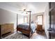 A bedroom features a four-poster bed, hardwood floors, and windows with natural light at 7626 Timber Springs S Dr, Fishers, IN 46038