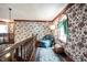The upstairs hallway features floral wallpaper, a cozy chair, and a clerestory window at 7626 Timber Springs S Dr, Fishers, IN 46038