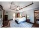 A well-lit main bedroom features tray ceilings, hardwood floors, and a view to the en suite bathroom at 7626 Timber Springs S Dr, Fishers, IN 46038