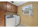 Laundry room with matching washer and dryer, wood cabinets, and natural light, enhancing the home's convenience at 8140 Valley Estates Dr, Indianapolis, IN 46227