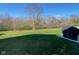 Lush green backyard featuring wooded area, partially covered patio, and covered grill at 9074 Larson Dr, Pendleton, IN 46064