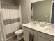 Bathroom featuring double sinks, white cabinets, and shower with gray striped curtain at 9074 Larson Dr, Pendleton, IN 46064