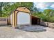 This tan shed features a white garage door and light trim with a gravel lot in front at 9510 N Cooney Rd, Mooresville, IN 46158