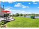 Sprawling backyard featuring lush green grass, a patio set with a red umbrella, and lake views at 9557 W Lantern Ln, Pendleton, IN 46064