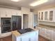 Well-lit kitchen with white cabinets, granite countertops, a black refrigerator, and a kitchen island with stovetop at 9909 E Mcgregor Rd, Indianapolis, IN 46259