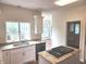 Bright kitchen with island cooktop, granite countertops, white cabinets, and a stainless steel sink beneath a window at 9909 E Mcgregor Rd, Indianapolis, IN 46259