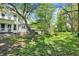 Expansive backyard featuring mature trees, lush green grass, and a cozy seating area with a bench and fire pit at 1000 E King St, Franklin, IN 46131