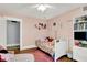A cozy bedroom featuring a pink color scheme, a single bed with decorative pillows, and a white bookshelf at 1000 E King St, Franklin, IN 46131