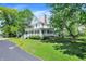Charming white home with a covered porch, complemented by a lush green lawn and mature trees at 1000 E King St, Franklin, IN 46131