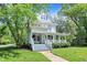 Inviting white home with a welcoming covered porch, nestled amidst mature trees and a green lawn at 1000 E King St, Franklin, IN 46131