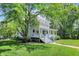 Classic white home with a spacious covered porch, enhanced by a verdant lawn and mature shade trees at 1000 E King St, Franklin, IN 46131