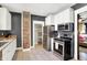 Well-lit kitchen featuring stainless steel appliances, white cabinets, a brick accent, and tile flooring at 1124 E 35Th St, Indianapolis, IN 46205