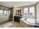 Well-lit bathroom with a glass-enclosed shower, soaking tub, and dark wood cabinets at 11323 Still Creek Dr, Zionsville, IN 46077