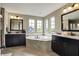 Bright bathroom featuring granite countertops, dark cabinetry, a garden tub, and large windows at 11323 Still Creek Dr, Zionsville, IN 46077