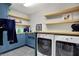 Laundry room with blue cabinets, floating wood shelves, washer and dryer at 11323 Still Creek Dr, Zionsville, IN 46077
