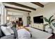 Comfortable living room featuring exposed beams, modern furnishings, stylish rug, and open access to dining and kitchen areas at 11323 Still Creek Dr, Zionsville, IN 46077