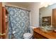 Bathroom with blue floral shower curtain, toilet, and transparent vessel sink at 1157 Fielding Ln, Franklin, IN 46131