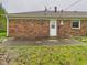 Backyard view of brick home featuring a small patio area and well-maintained lawn at 1209 S Rangeline Rd, Anderson, IN 46012