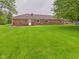 Well-manicured backyard featuring a brick home with a manicured lawn and mature trees at 1209 S Rangeline Rd, Anderson, IN 46012