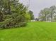 View of the lush green front lawn and distant street with trees adding a natural touch at 1209 S Rangeline Rd, Anderson, IN 46012