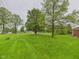 Expansive front yard featuring lush green grass, mature trees, and well-maintained landscaping at 1209 S Rangeline Rd, Anderson, IN 46012