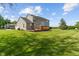 Back of home features a wood deck, green lawn, and mature trees on a sunny day at 13553 Lorenzo Blvd, Carmel, IN 46074