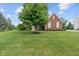 Brick house with a well-manicured lawn and mature shade trees on a sunny day at 13553 Lorenzo Blvd, Carmel, IN 46074