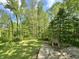 View of the tree-filled backyard featuring a brick outdoor fireplace and concrete patio at 1760 Pumpkinvine Hill Rd, Martinsville, IN 46151