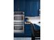 Kitchen featuring stainless double ovens, white backsplash, and ample blue cabinets at 1787 Halifax St, Carmel, IN 46032