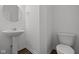 Powder room with white pedestal sink, toilet, and wood-look floors at 1874 Victor Higgins Dr, Shelbyville, IN 46176