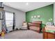 Bright bedroom with a cozy crib, rocking chair, and cheerful green accent wall at 2006 Monticlair Ln, Columbus, IN 47201