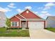 Charming single-story red home with a well-manicured lawn, white trim, and an attached two-car garage at 2006 Monticlair Ln, Columbus, IN 47201
