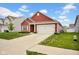 Attractive single-story red home with a two-car garage, green lawn and tidy landscaping at 2006 Monticlair Ln, Columbus, IN 47201