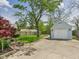 Spacious backyard with mature tree, lush lawn, garden beds, and a detached garage at 2011 Sheffield Ave, Anderson, IN 46011