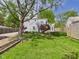 Lush backyard with a large tree, green lawn, garden beds, and a swing at 2011 Sheffield Ave, Anderson, IN 46011