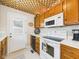 Well-equipped kitchen with white appliances, light wood cabinets, and a unique ceiling design at 2011 Sheffield Ave, Anderson, IN 46011