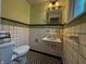 Stylish bathroom with black and white checkered floors, tiled walls, and a vintage-style sink and mirror at 333 N Kenyon St, Indianapolis, IN 46219