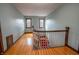 Second floor hallway with hardwood floors and traditional banister leading to stairs with red carpet at 333 N Kenyon St, Indianapolis, IN 46219